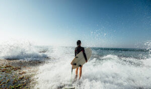 Woman surfer with surfboard going to surf at seaside